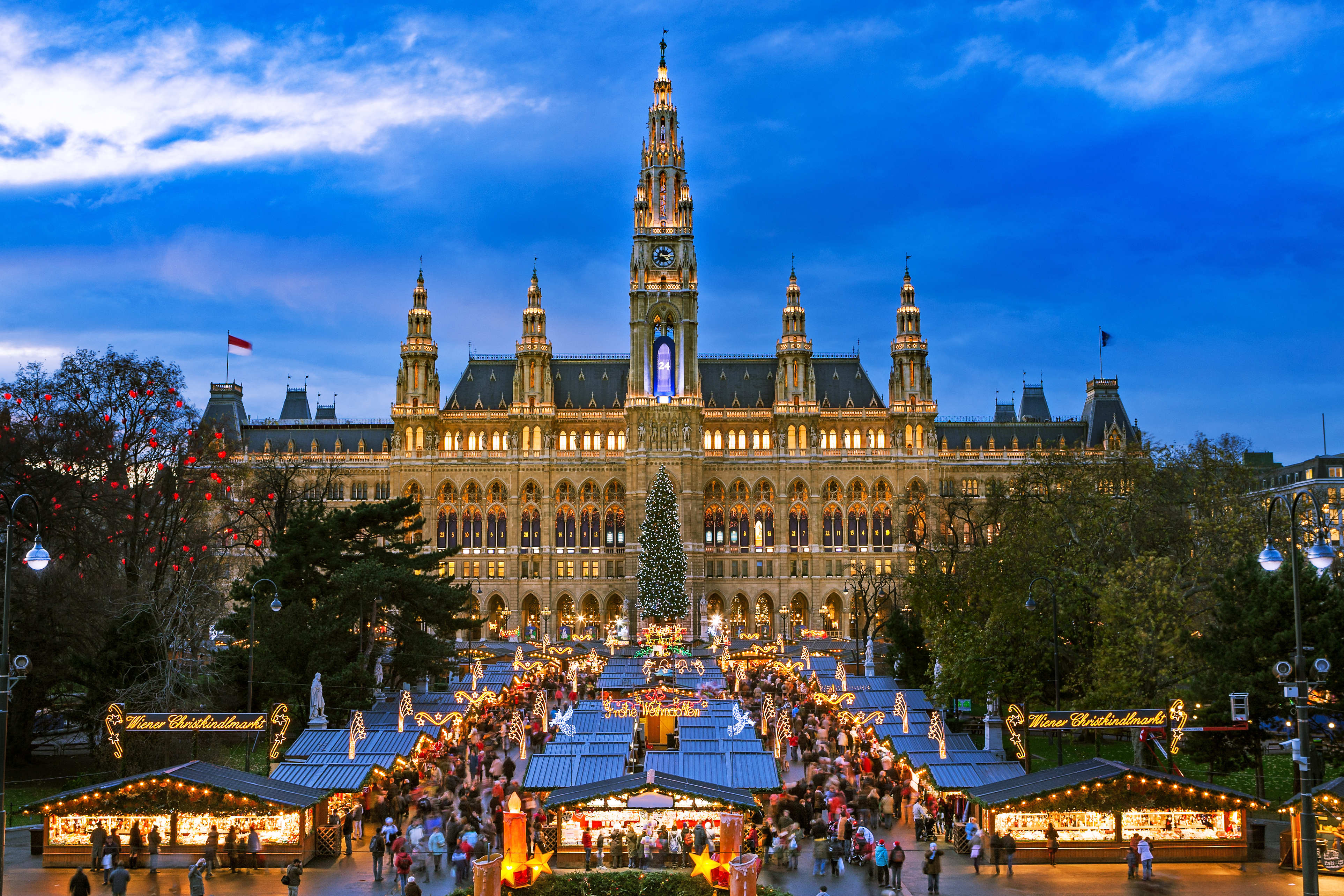 Eventyrligt julemarked i Wien med tusindvis af julelys, traditionelle markedsboder og et smukt pyntet juletræ foran det majestætiske rådhus på den berømte Rathausplatz