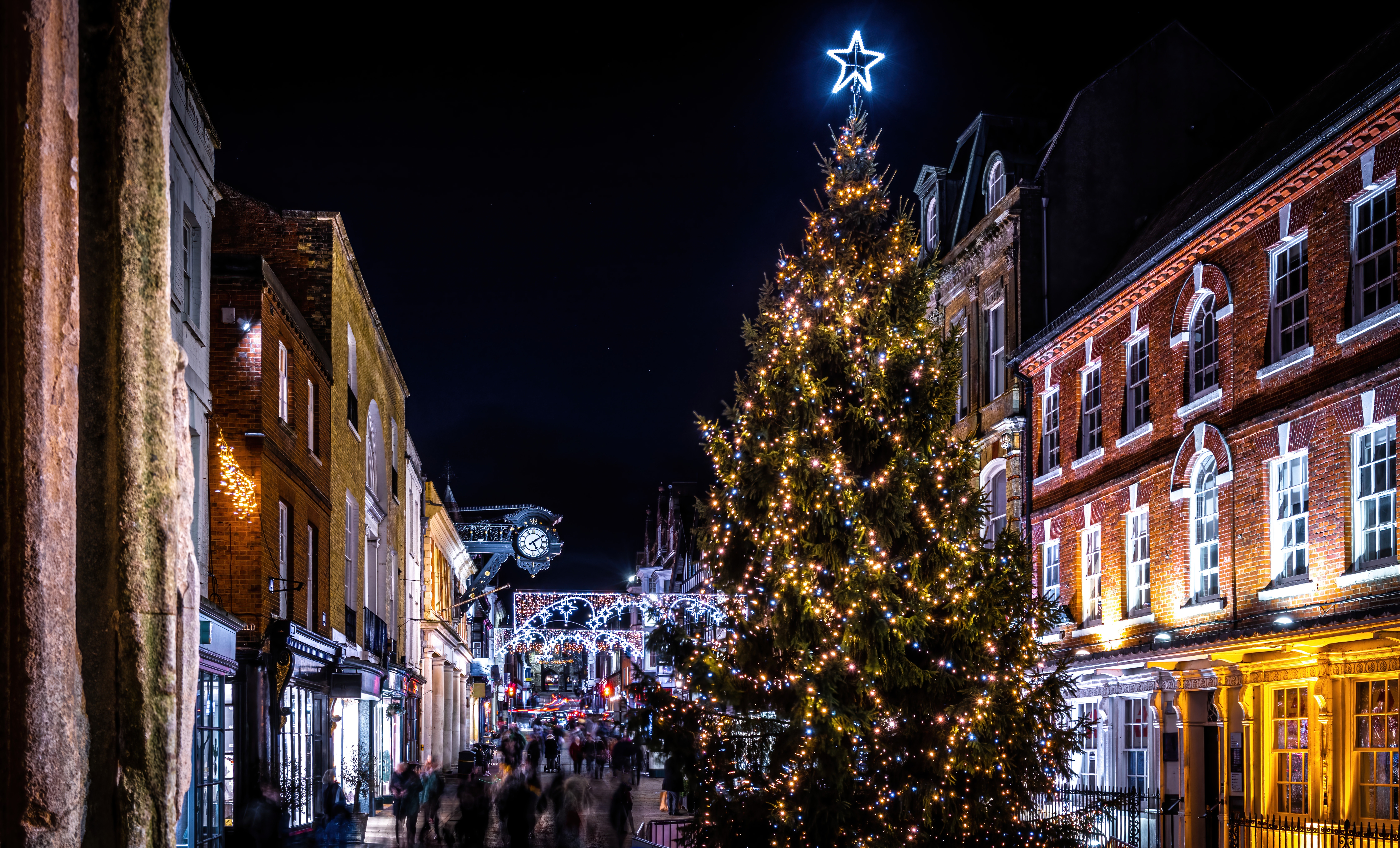 Julestemt Winchester High Street med historiske bygninger, strålende julelys og et stort juletræ i Hampshire, England