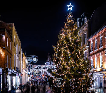 Julestemt Winchester High Street med historiske bygninger, strålende julelys og et stort juletræ i Hampshire, England