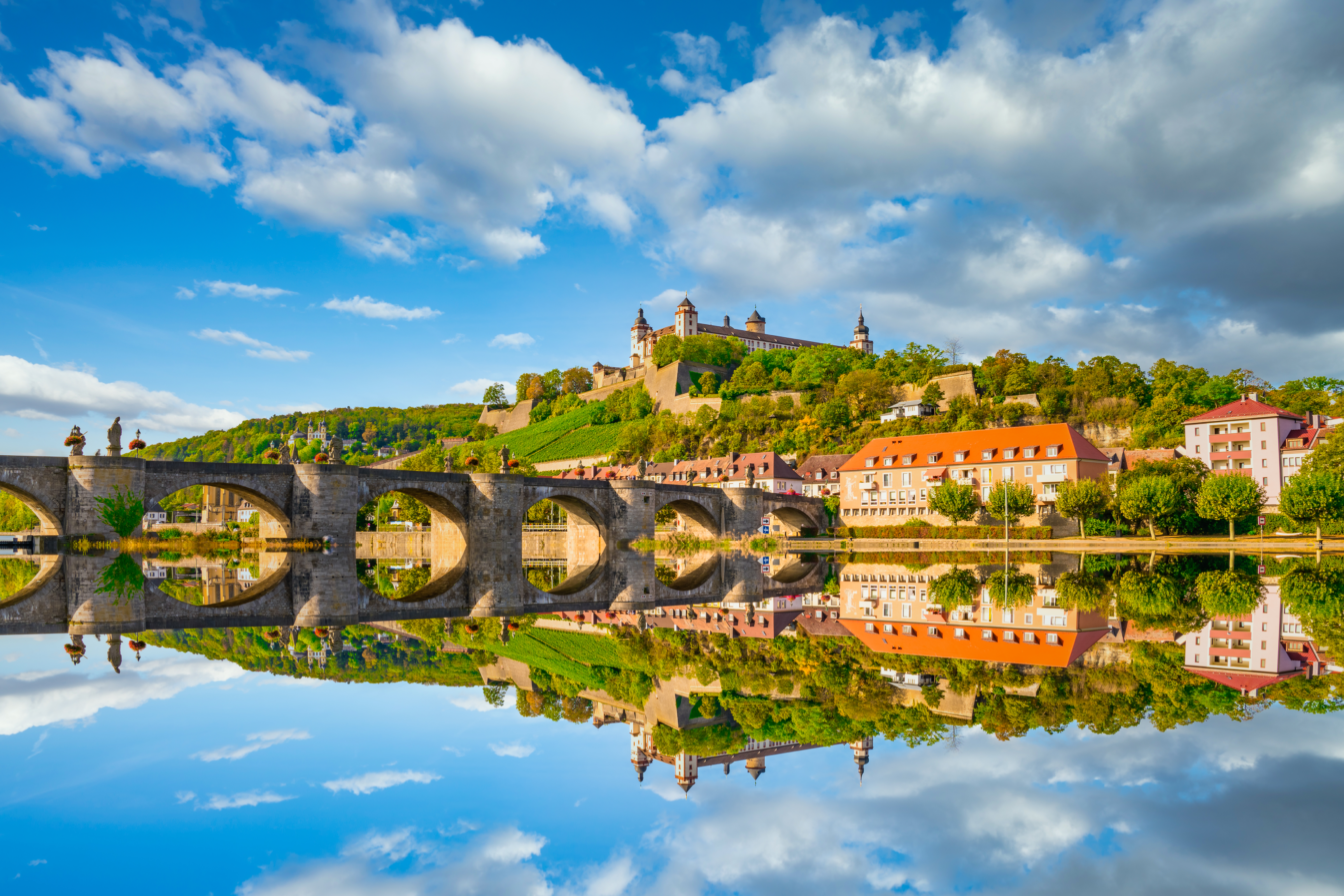 Smuk udsigt over Würzburg i Bayern med Marienberg Fæstning, middelalderlig stenbro og rolige vandrefleksioner i Main-floden på en solrig dag