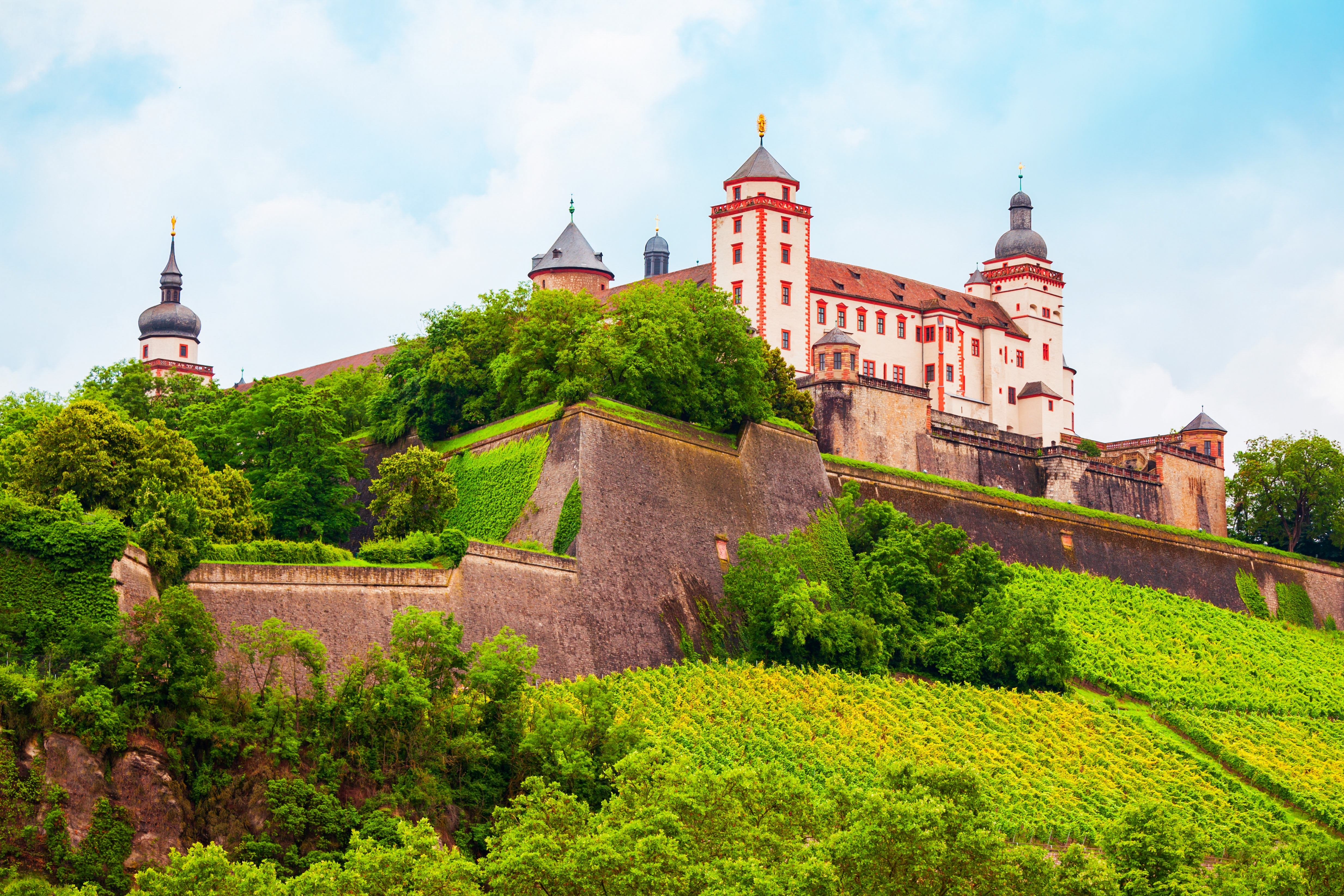 Historisk Marienberg Fæstning i Würzburg med grønne vinmarker i forgrunden og middelalderlige tårne mod skyfri himmel i Franken