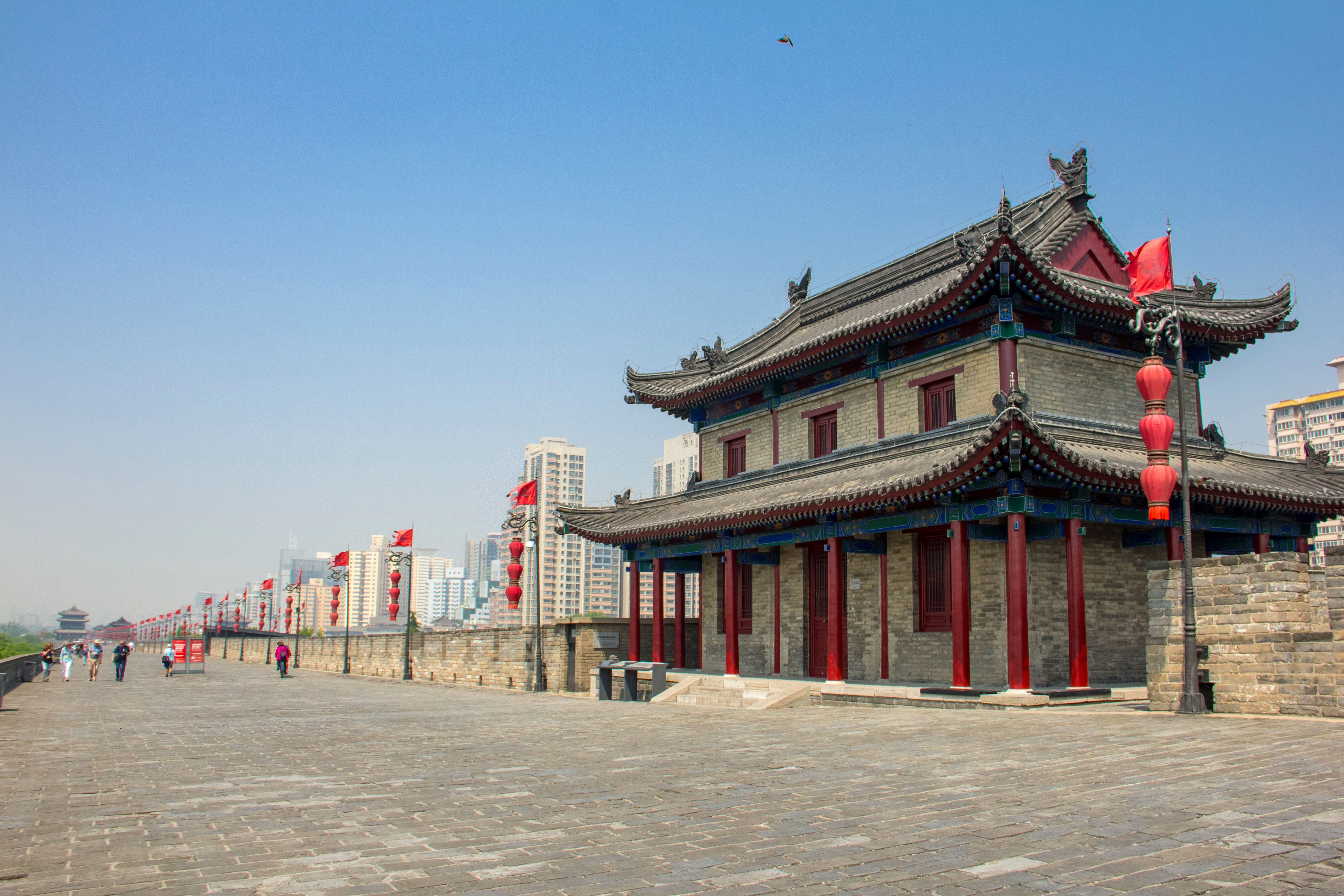 Majestætisk bymur i Xi'an med kinesisk vagttårn og røde lanterner langs murens top – oplev Kinas historiske storhed