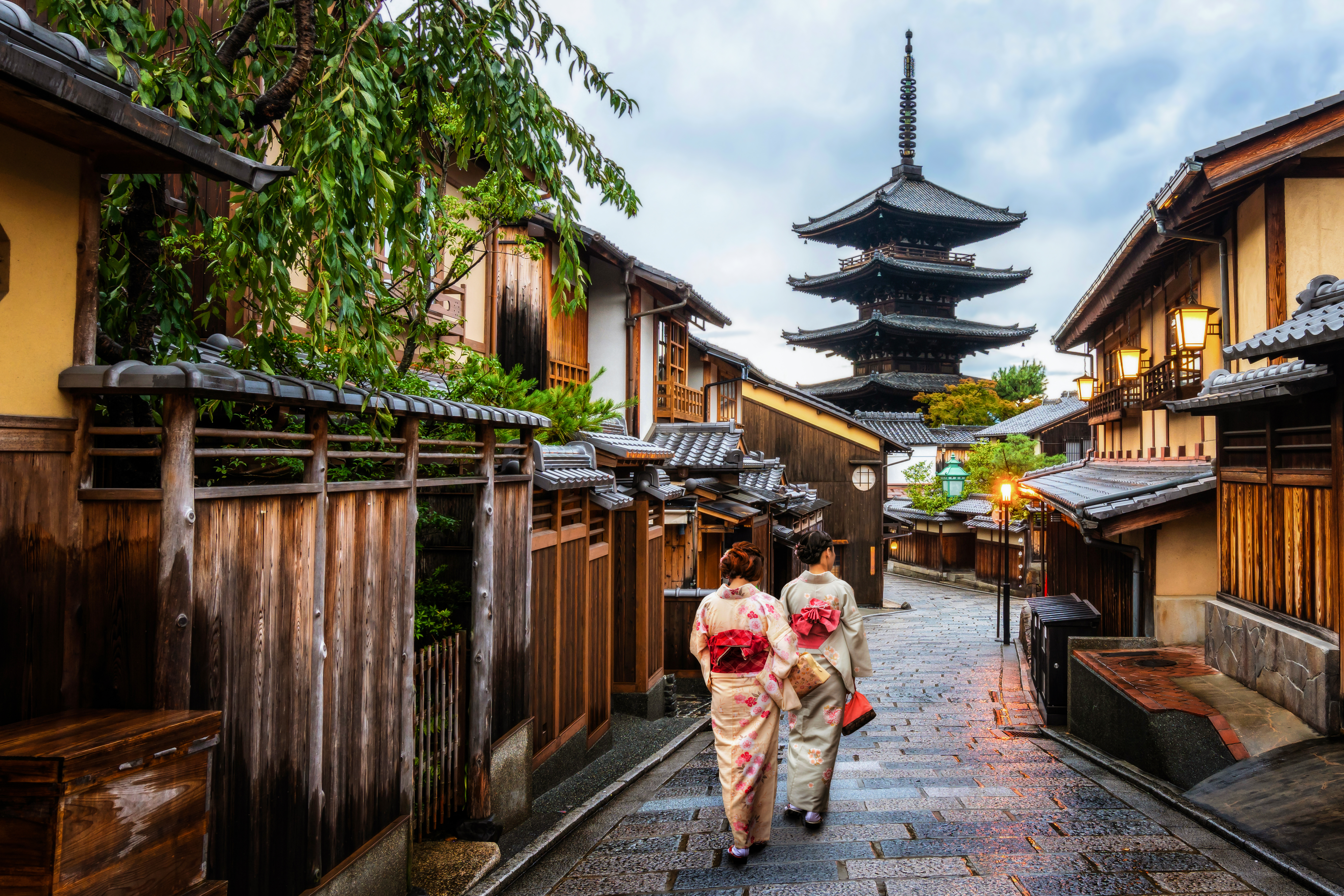 Malerisk japansk scene med kvinder i farverige kimono på historisk stenbelagt gade i Kyoto
